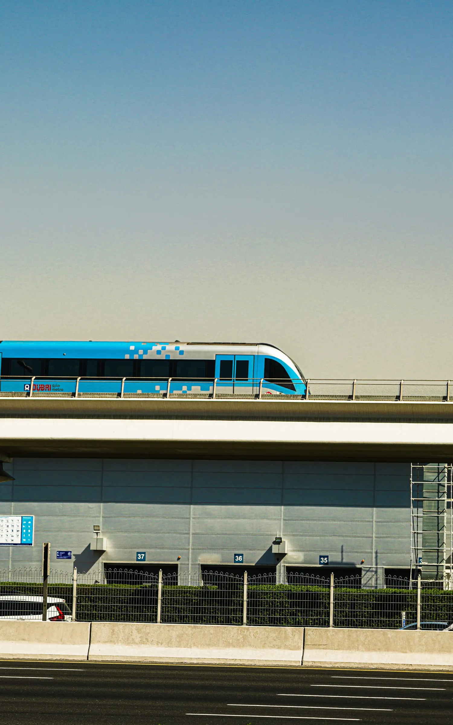 A Dubai Metro train on an elevated viaduct under a clear sky
